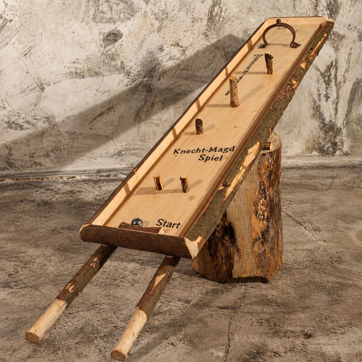 Knecht-Magd-Spiel aus hellem Holz mit Rindenkanten, fünf Aststiften als Hindernisse, schmiedeeisernem Zielbügel und Metallkugel – traditionelles Balancierspiel zum Mieten im Hochschwarzwald