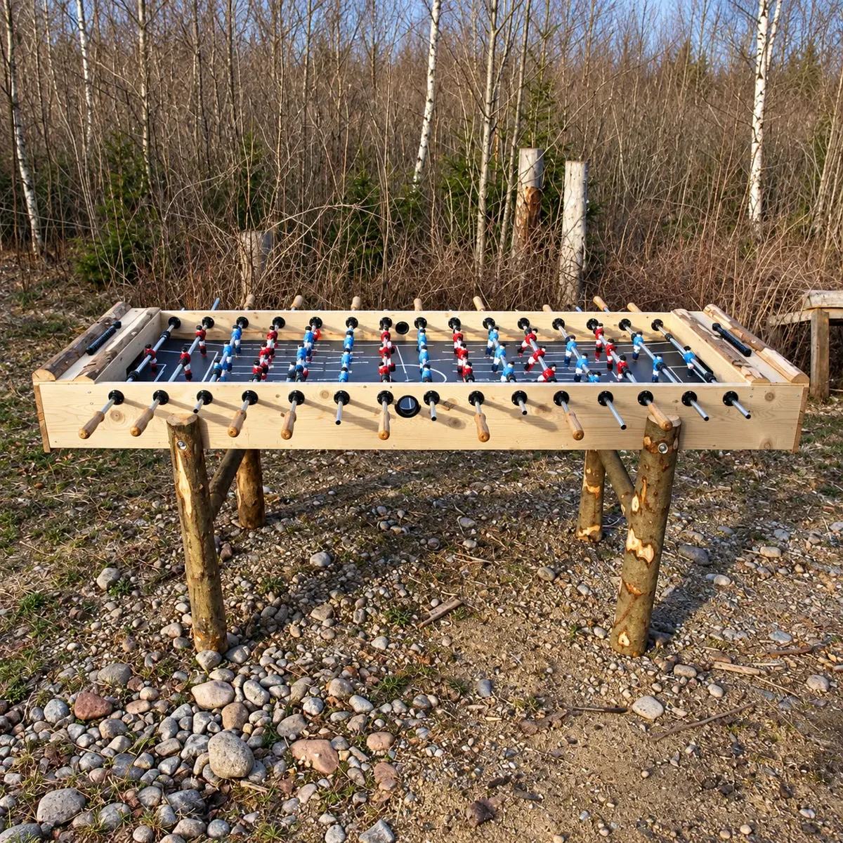 XXL Tischkicker: extra langer Tischkicker mit Holzrahmen, roten und blauen Spielfiguren und Beinen aus Naturstämmen im Freien – Holzspiel zum Mieten im Hochschwarzwald