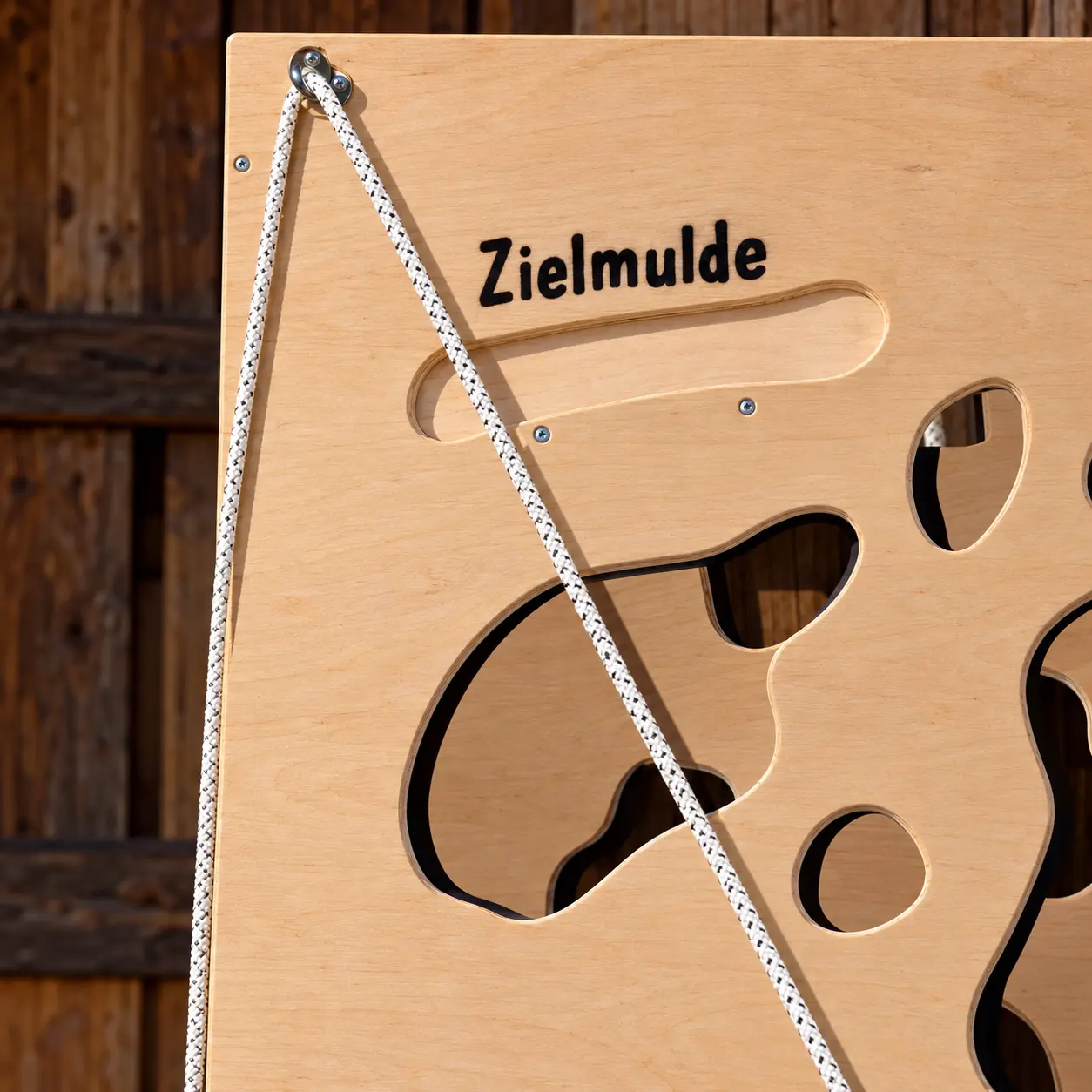 Ballkletterwand im Detail: Zielmulde oben, Seilzug und ausgeschnittene Kuhflecken im Holz