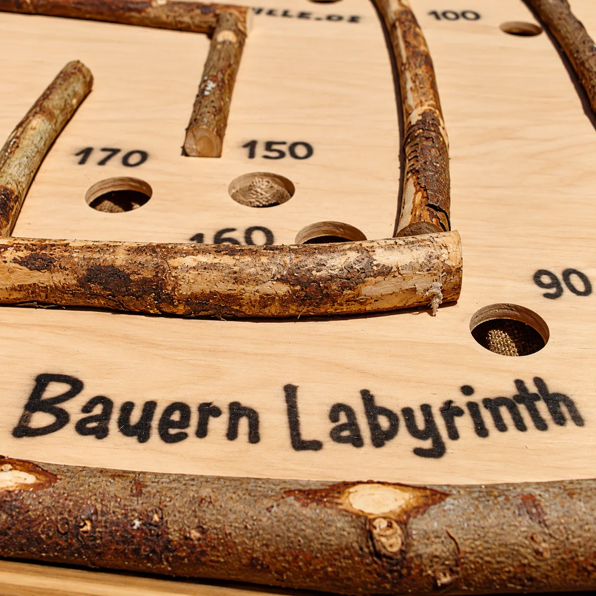Detail des Bauern Labyrinth: aufgedruckter Schriftzug „Bauern Labyrinth“ und Punktefelder zwischen den hölzernen Begrenzungsleisten