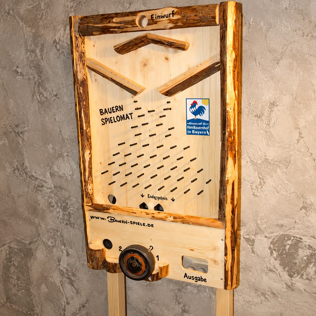 Bauern-Spielomat aus hellem Holz: mechanischer Spielautomat mit Einwurföffnung oben, Nagelbrett-Labyrinth, Drehrad und Ausgabefach unten