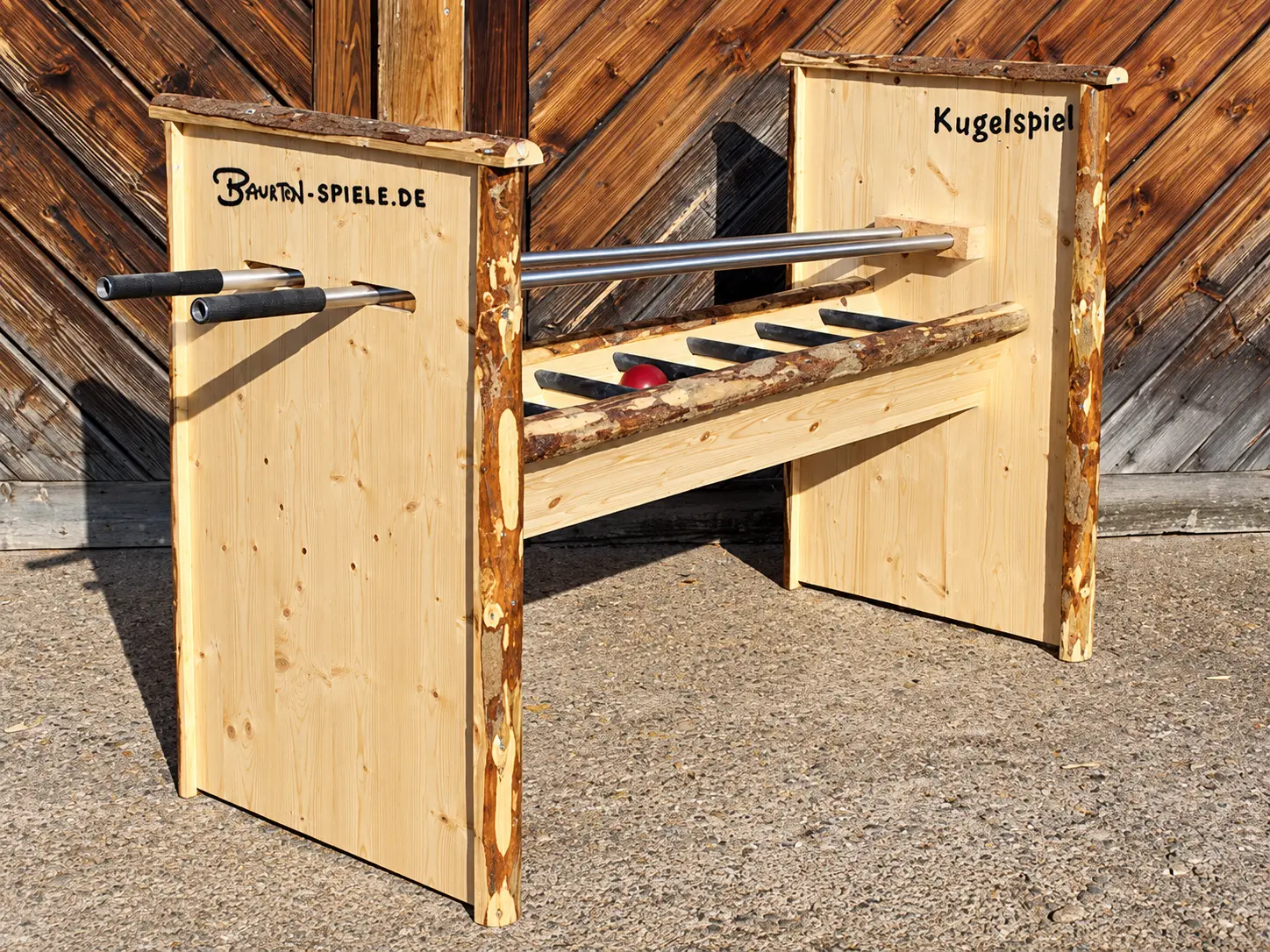 Kugelspiel aus hellem Massivholz mit zwei Metallstangen und roter Kugel – traditionelles Geschicklichkeitsspiel zum Mieten im Hochschwarzwald