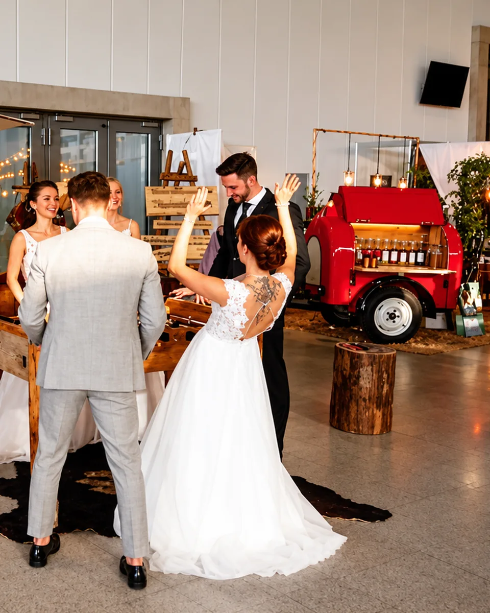 Braut und Bräutigam spielen bei einer Hochzeit an einem hölzernen Tischkicker