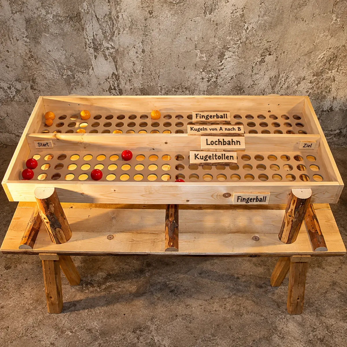 Lochbrett-Spieltisch aus Holz mit zwei Bahnen, roten und gelben Kugeln, Schildern „Fingerball“, „Lochbahn“, „Start“ und „Ziel“ auf Holzböcken